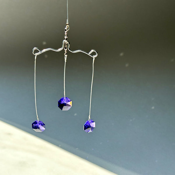 three purple crystal suncatchers on a gray background