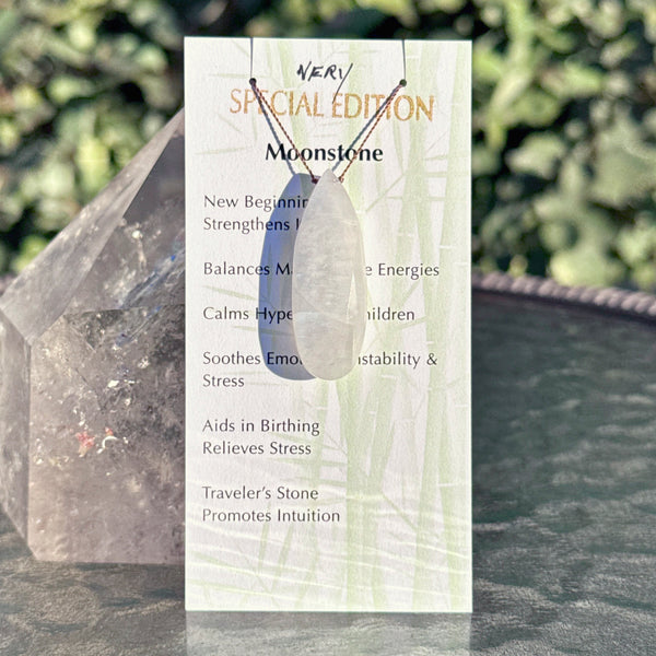 Moonstone earrings with a card detailing stone properties against a natural background